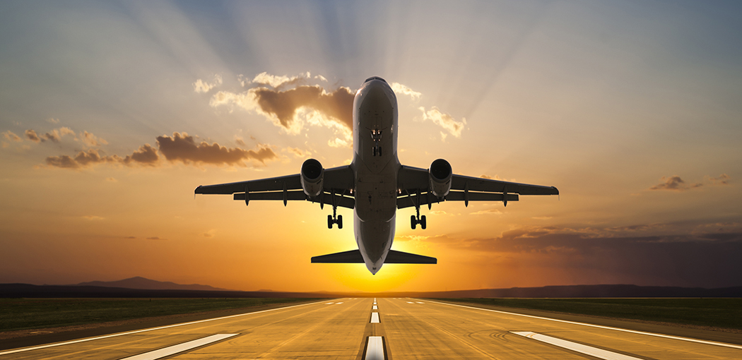 Passenger jet airplane taking off at sunset